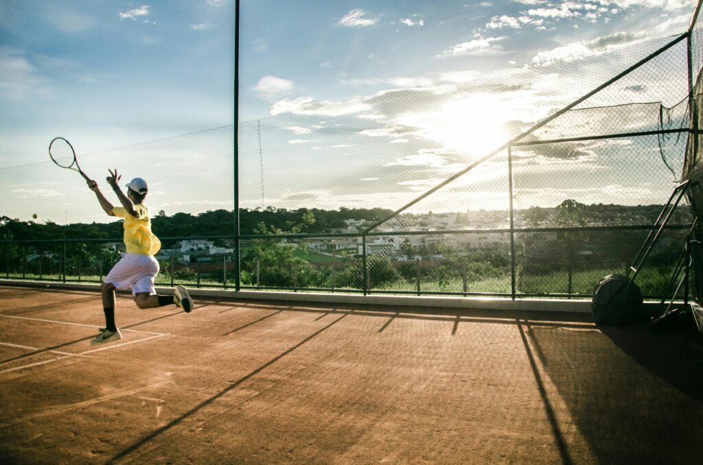 Capture the intensity of a young athlete performing on an outdoor tennis court at sunset.
